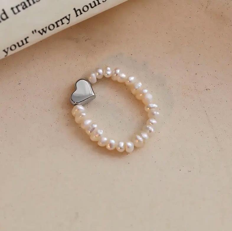 En nydelig justerbar ring fra Ella & Pia med strikk og perler. Hjertet er laget av 925 Stearling Silver belagt med rhodium. Ringen veier 1,4g. Alle smykkene fra Ella & Pia nikkel- og blyfri.
